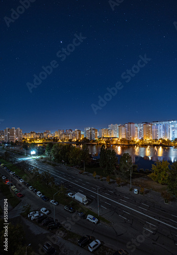 Night cityscape of the big city under starry sky. Awesome bright, multi colored light at curfew on empty streets. Apartment buildings in bedroom town area. Kyiv in mid october 2022. Ukraine. photo