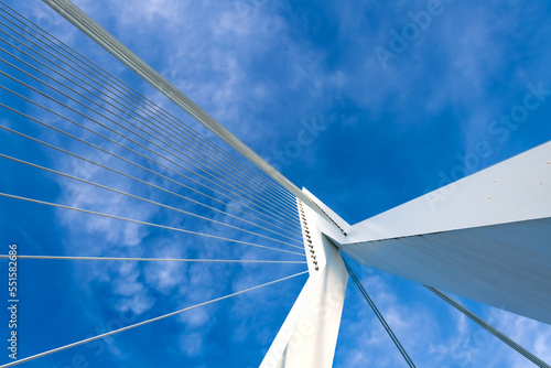 Steel cables and white metal construction from frog perspective with blue sky. Diagonal lines and bridge details with vanishing point.