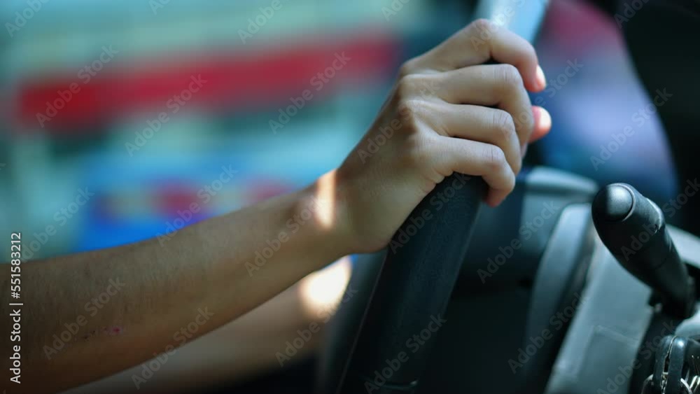 Female driver hands holding steering wheel driving in city. Closeup person hand commuting Female driver hands holding steering wheel driving in city. Closeup person hand commuting