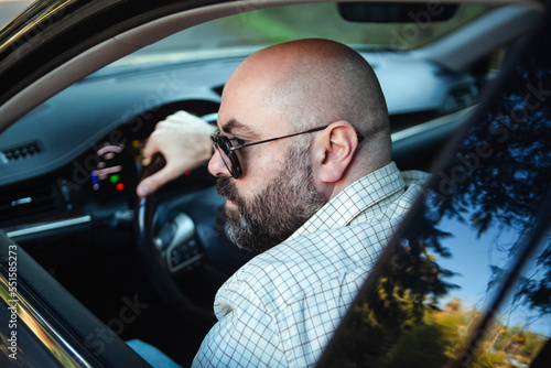 brutal bald bearded middle-aged man drives a car