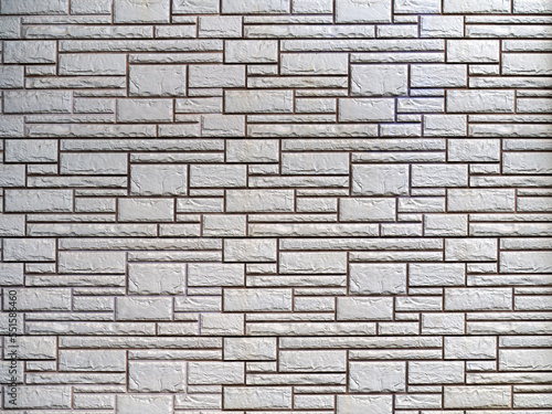 The gray brick wall consists of rough decorative bricks of various sizes and shapes. Abstract geometric stone background.