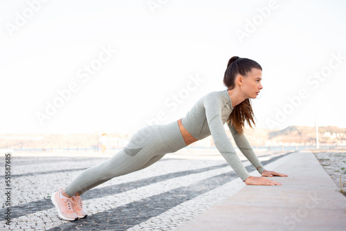 Young attractive girl athlete in sportswear performing push-ups on concrete step