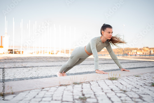 Young attractive girl athlete in sportswear performing push-ups on concrete step