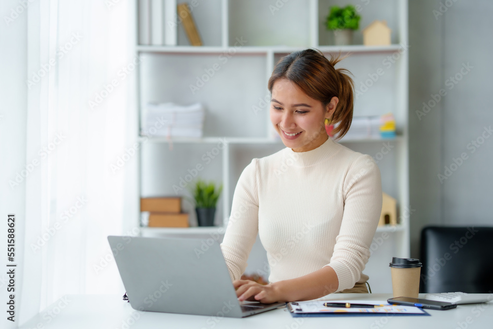 Beautiful young Asian businesswoman sitting working with laptop thinking about new ideas for her work with a bright and happy face. Beautiful young Asian businesswoman sitting working with laptop thinking about new ideas for her work with a bright and happy face.