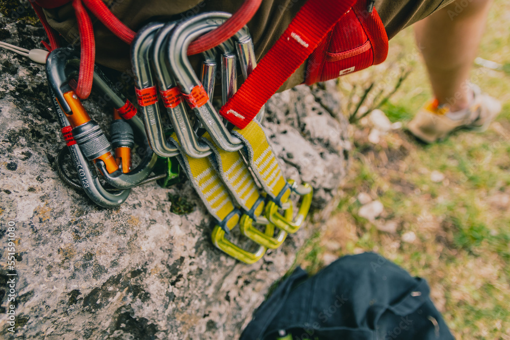 Fototapeta premium A man sitting on a sheet with a rope, getting ready to climb by tying his boots. he is wearing a harness and equipment