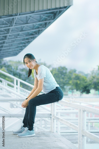 Portrait of sitting Asian woman thinking in stadium, happy time smiling