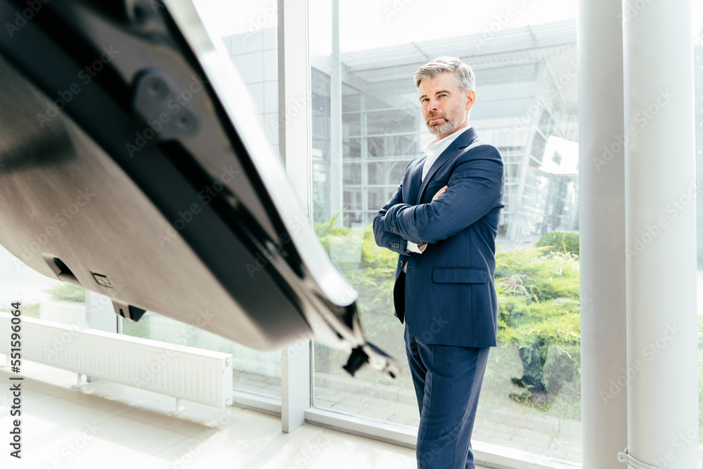 Stylish middle age grey hair businessman opens the pen the car trunk. Aged client looking inside the luggage compartment of the vehicle. Stylish middle age grey hair businessman opens the pen the car trunk. Aged client looking inside the luggage compartment of the vehicle.