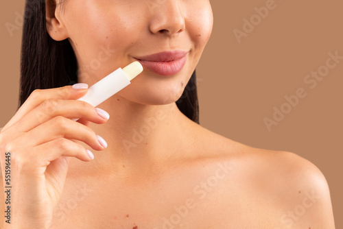 Cropped of topless woman applying lipbalm on her soft lips