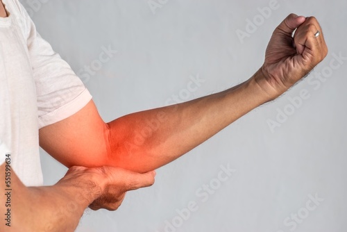 Pain in the elbow joint of Asian young man. Concept of elbow pain, injury, rheumatism or osteoarthritis. photo