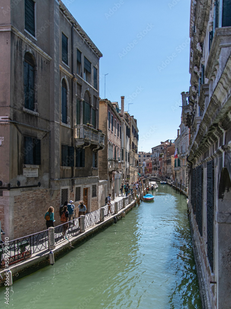 Touristen laufen auf einem Fussweg an einem Kanal in der Altstadt von Venedig