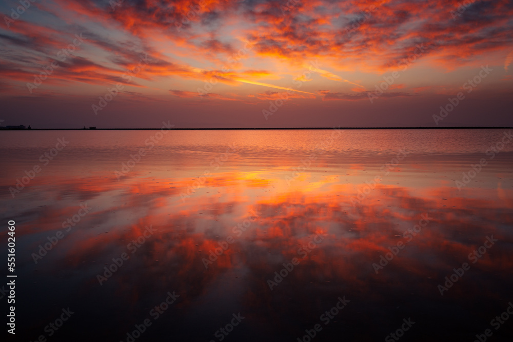 Sea landscape with vivid colorful clouds reflecting in still water just before sunrise, Dahab, Egypt