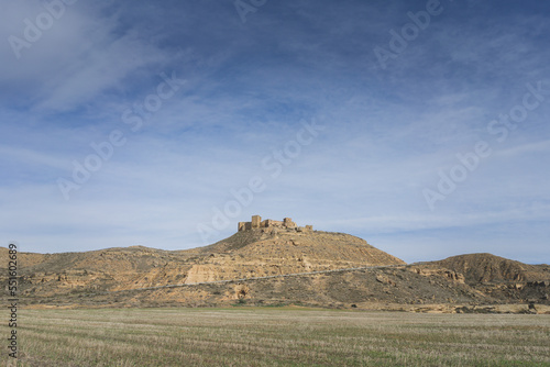 Dry landscape with a mountain on the horizon and at the top is the medieval castle of Montearag  n with many ruins inside. Huesca  Spain