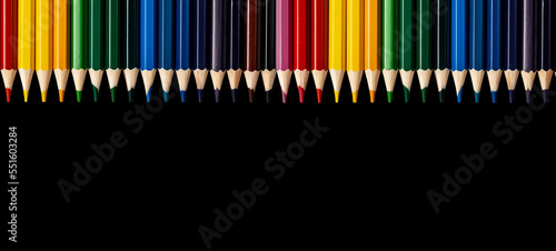 Colored pencils on black background. Promo banner with copy space for text, multi coloured art supplies. Ad for drawing school photo