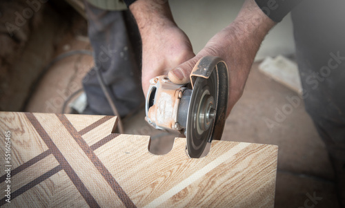 Worker cutting a ceramic tile with a grinder.