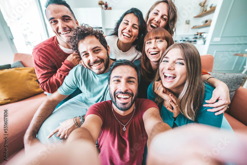 Group of friends taking selfie with smart mobile phone device at home - Happy young people smiling together at camera - University students having fun together in college campus - Friendship concept © Davide Angelini
