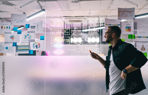 Focused man looking at data on glass wall in meeting room in office