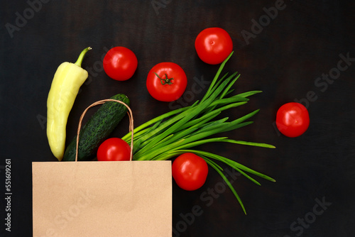 Vegetables in a paper bag on a dark background with a top view. The concept of food in bags. Healthy vegetarian food. Food delivery.