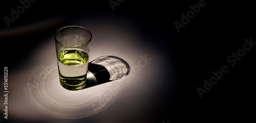 Green glass with water on a black background. Text space. Bright light.