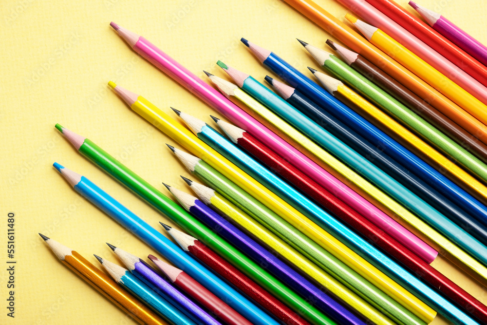 There are many different colored pencils scattered on a colored background. There are many different colored pencils scattered on a colored background.