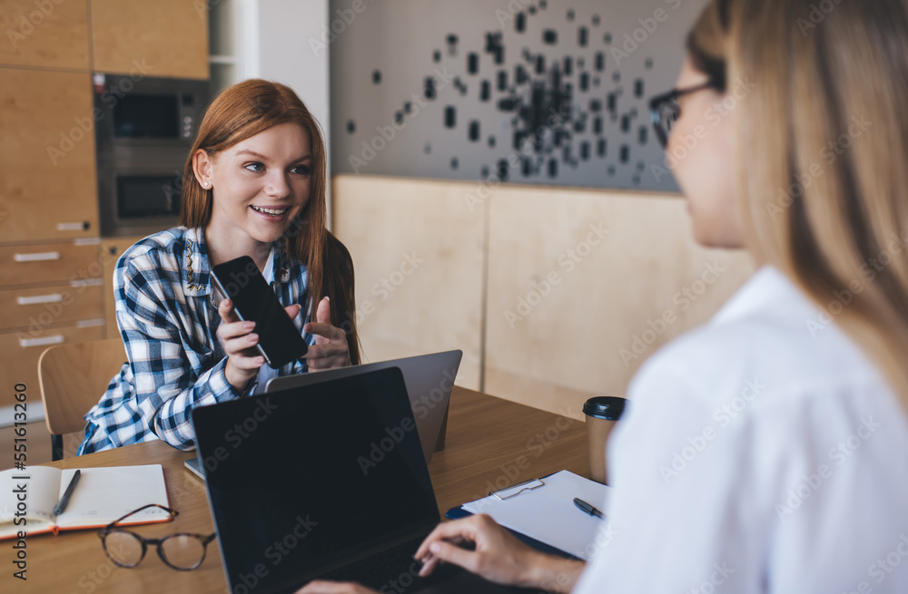 Smiling women with laptops working together