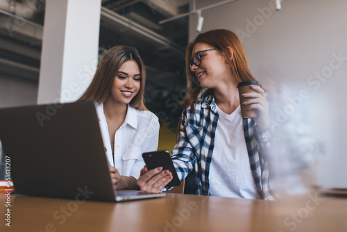 Smiling women using gadgets and drinking coffee during break