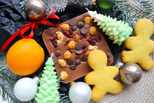 Cristmas presents. christmas sweets. chocolate with nuts and candied fruit, gingerbread, tangerines, Christmas tree branches and Christmas balls 