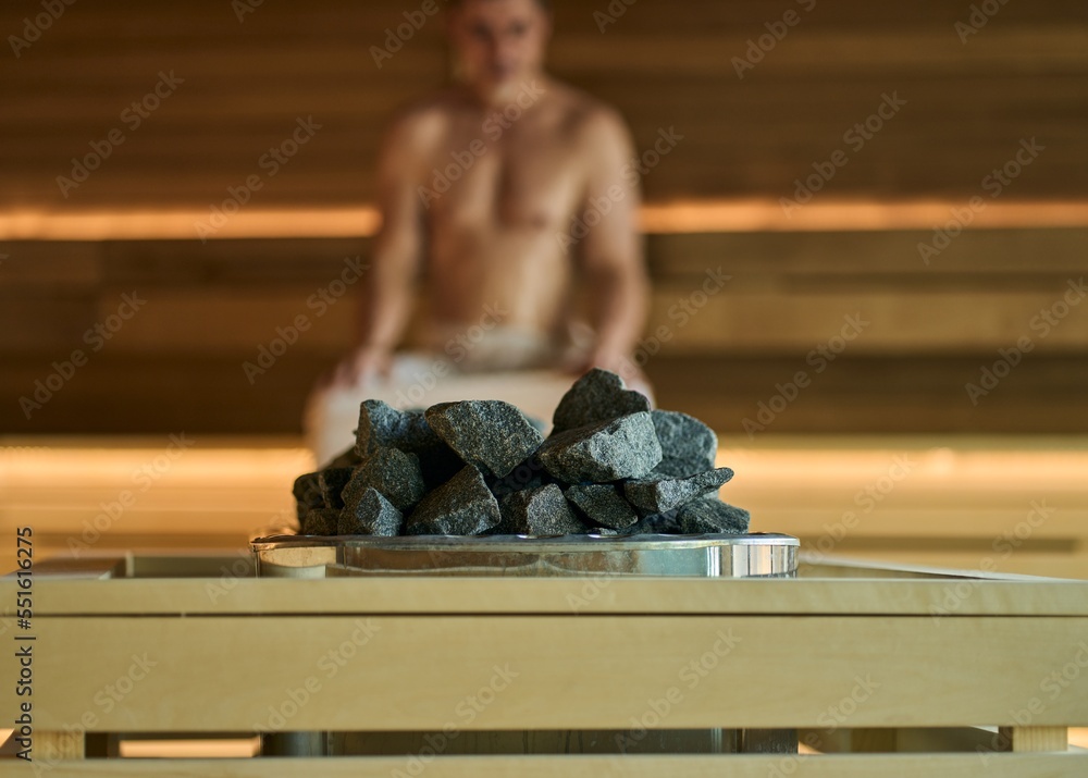 Man relaxing in wellness spa, sweating in Finnish sauna, focus on sauna