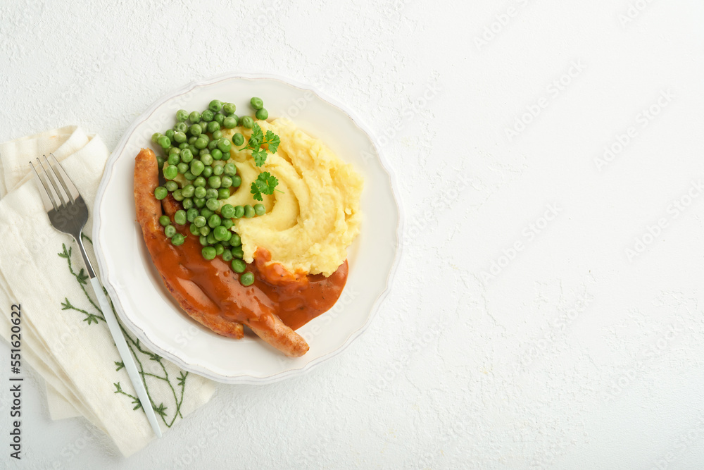 Bangers and mash. Grilled sausages with mash potato and green pea on white plate on light background. Traditional dish of Great Britain and Ireland. BBQ beef sausages. Top view.