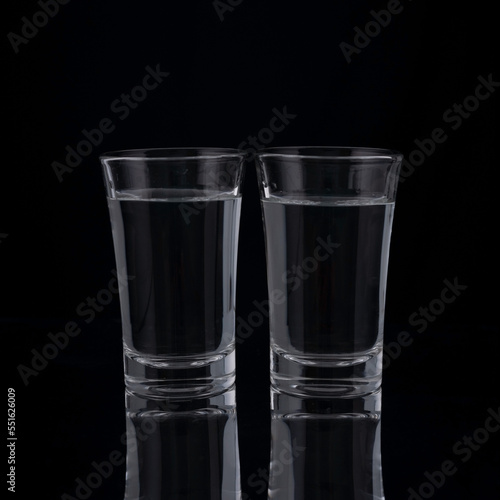 shot glasses with vodka on a black background