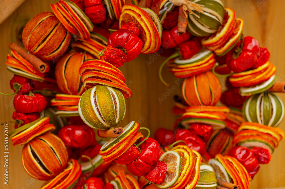 close up Christmas and New Year wreath with dried oranges, lime and spices on wooden rustic background. Citrus aroma and flavoring.
