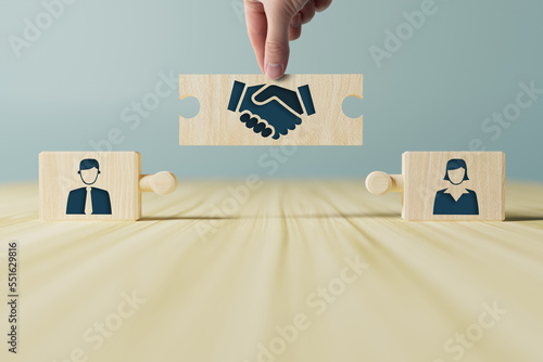 The hand holds wooden wooden blocks with icons of a woman and a man and shaking hands in the act of consent. The concept of divorce, agreement, mediation, the role of the mediator. photo