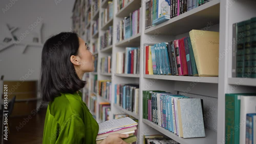 Young Asian teacher searches interesting books in library Young Asian teacher searches interesting books in library