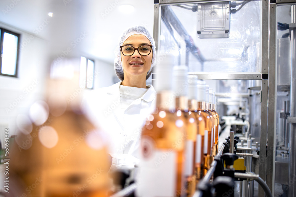 Portrait of female factory supervisor controlling wine production in alcohol beverage bottling plant.