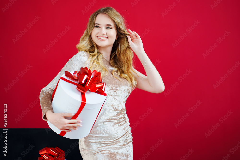 Fototapeta premium a beautiful woman in an elegant dress with a gift in the red room
