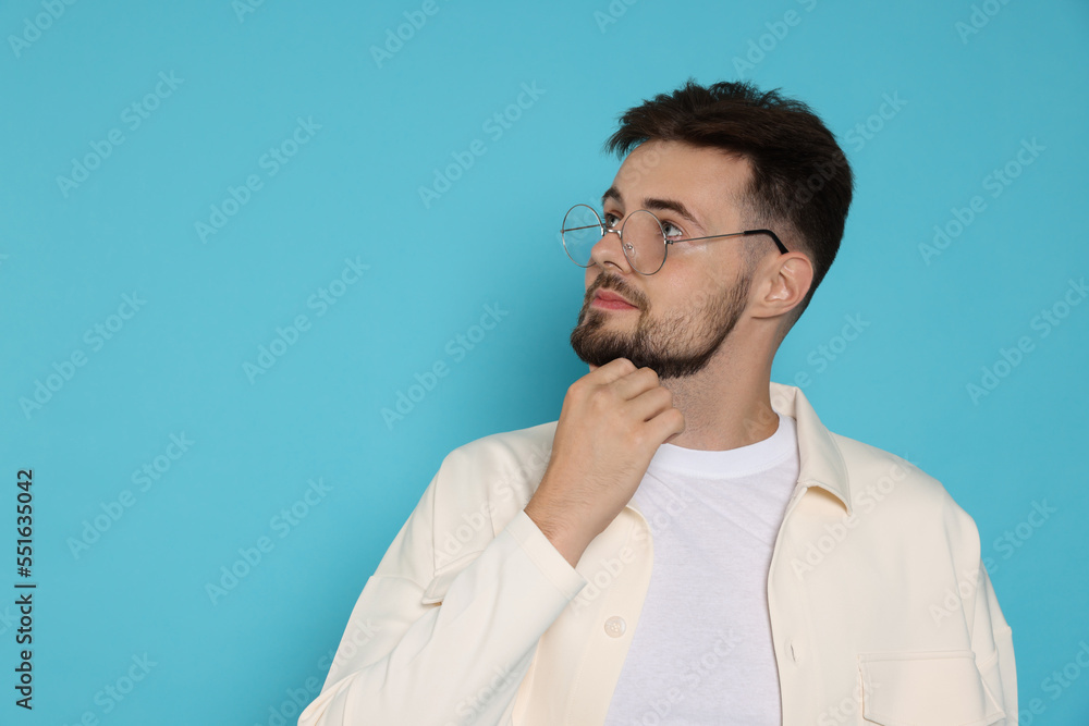 Thoughtful man in white jacket and eyeglasses on light blue background, space for text Thoughtful man in white jacket and eyeglasses on light blue background, space for text