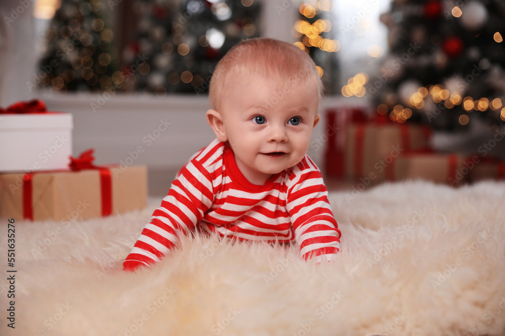 Cute baby in bright Christmas pajamas on floor at home Cute baby in bright Christmas pajamas on floor at home