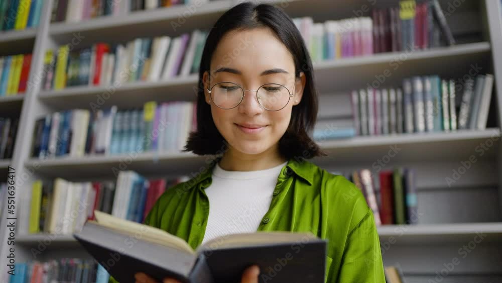 Young book-lover rests with pleasure reading book in library Young book-lover rests with pleasure reading book in library