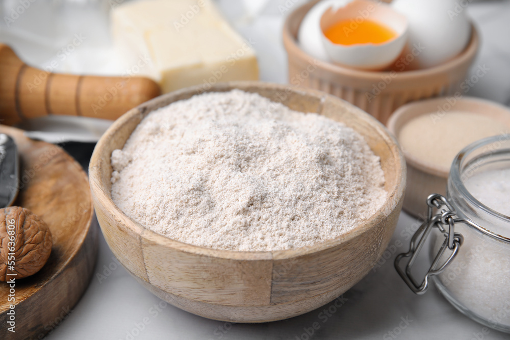 Bowl of flour and other ingredients on white table, closeup