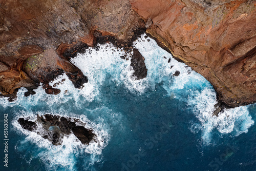 Rocky coastal peninsula Ponta de Sao Lourenco in Madeira island cliffside against dramatic ocean waves from drone view