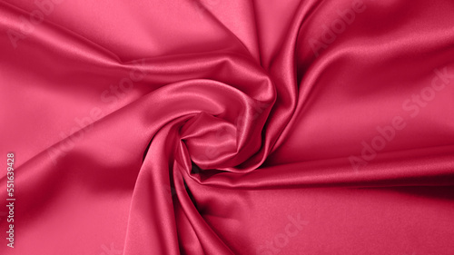 Viva Meganta toned red magenta fabric atlas. Close up pink silk satin texture for sewing. Abstract background wallpaper. Twisted folds cloth. Trendy color of the year 2023. Fashion color pattern