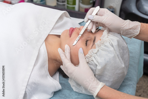 skin treatment with the dermaplaning technique performed with a scalpel by a beautician in a center of aesthetics and beauty of the body and skin