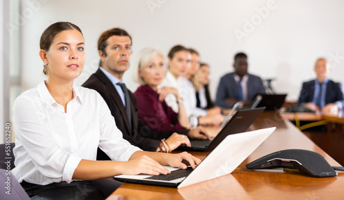 Young caucasian woman sitting at desk in meeting room and using laptop duting conference..