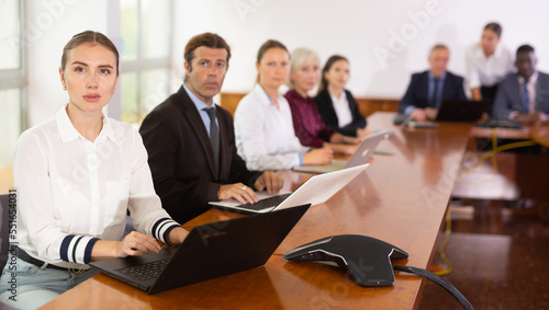 International group of business people listening to presentation at tables in conference room