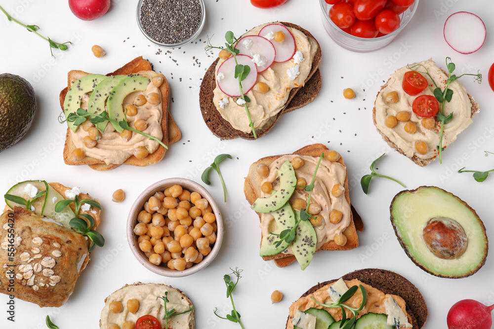 Delicious sandwiches with hummus and different ingredients on white background, flat lay