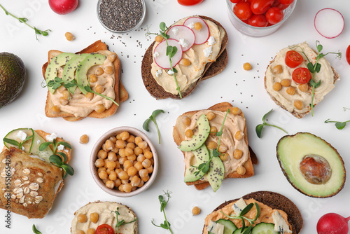 Delicious sandwiches with hummus and different ingredients on white background, flat lay