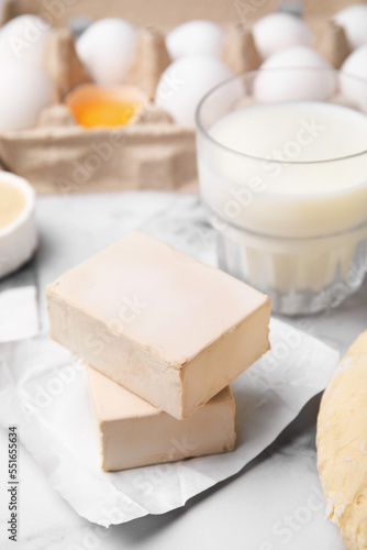 Blocks of compressed yeast and ingredients on white marble table, closeup