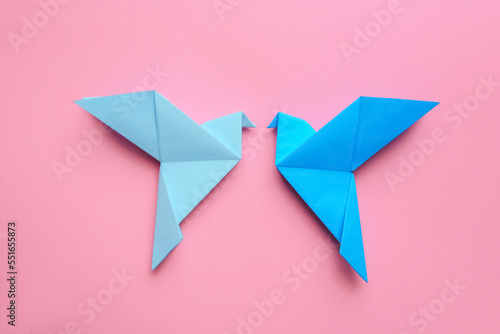 Beautiful light blue origami birds on pink background, flat lay