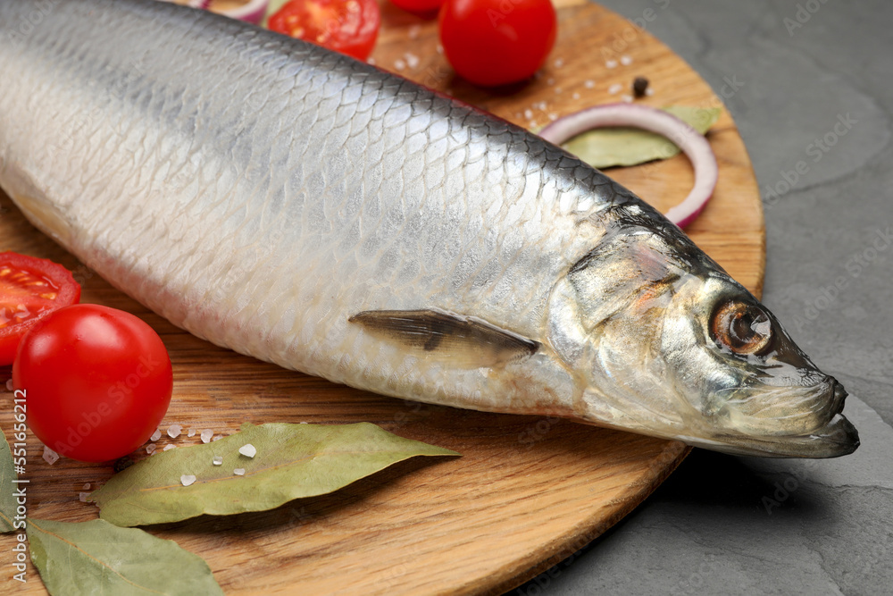 Tray with salted herring, onion, bay leaves and cherry tomatoes on black table, closeup Tray with salted herring, onion, bay leaves and cherry tomatoes on black table, closeup