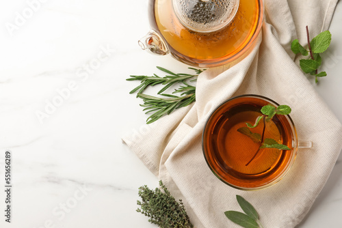 Aromatic herbal tea with rosemary, sage, thyme and mint on white marble table, flat lay. Space for text