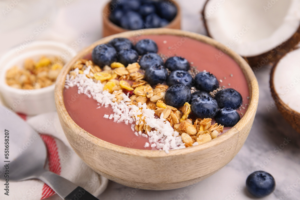 Bowl of delicious fruit smoothie with fresh blueberries, granola and coconut flakes on white marble table, closeup Bowl of delicious fruit smoothie with fresh blueberries, granola and coconut flakes on white marble table, closeup